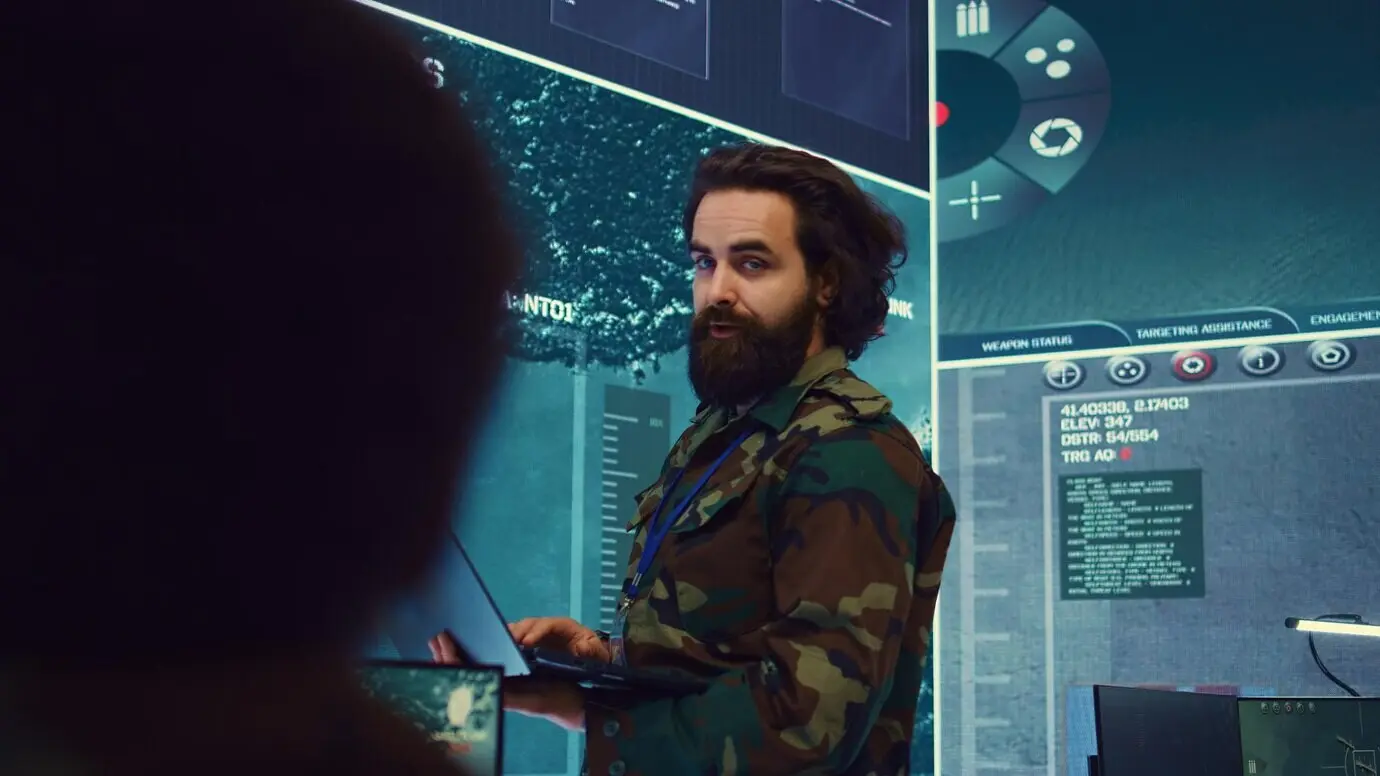 Майор армии отслеживает данные на большом экране в военном командном центре.